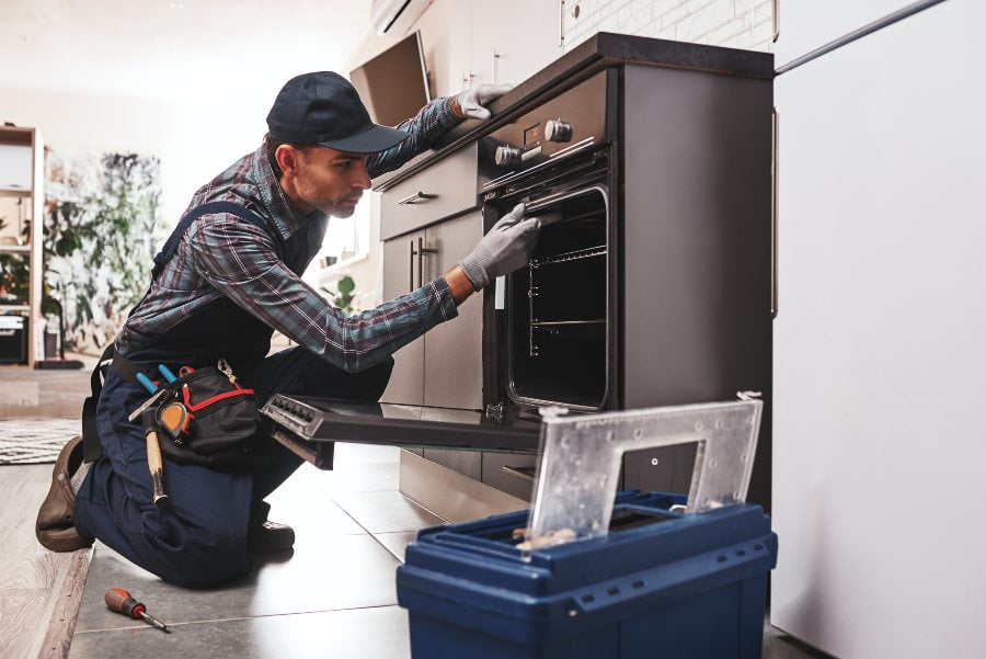 Professional licensed appliance repair technician fixing oven in San Diego home - Superior Appliance Repair expert providing same-day service